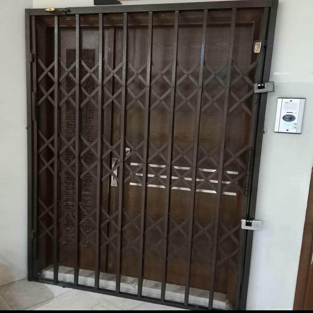 حفاظ درب آکاردئونی جمع شده کنار چهارچوب استان بوشهر